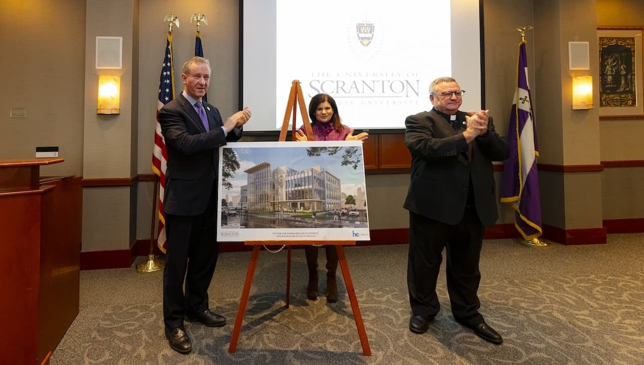 University of Scranton President Rev. Joseph G. Marina, S.J. (far right); Michelle Maldonado, Ph.D., provost and senior vice president for academic affairs (center); and U.S. Rep. Matt Cartwright (left) unveil the design for a center for workforce development, applied research and outreach, planned for the 300 block of Madison Avenue. The University received nearly $17 million in funding for the building from the National Institute of Standards and Technology.
